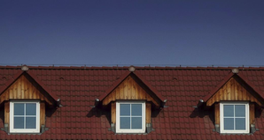 A picture of a red roof with clean roof shingles and spotless windows after a roof cleaning company 
